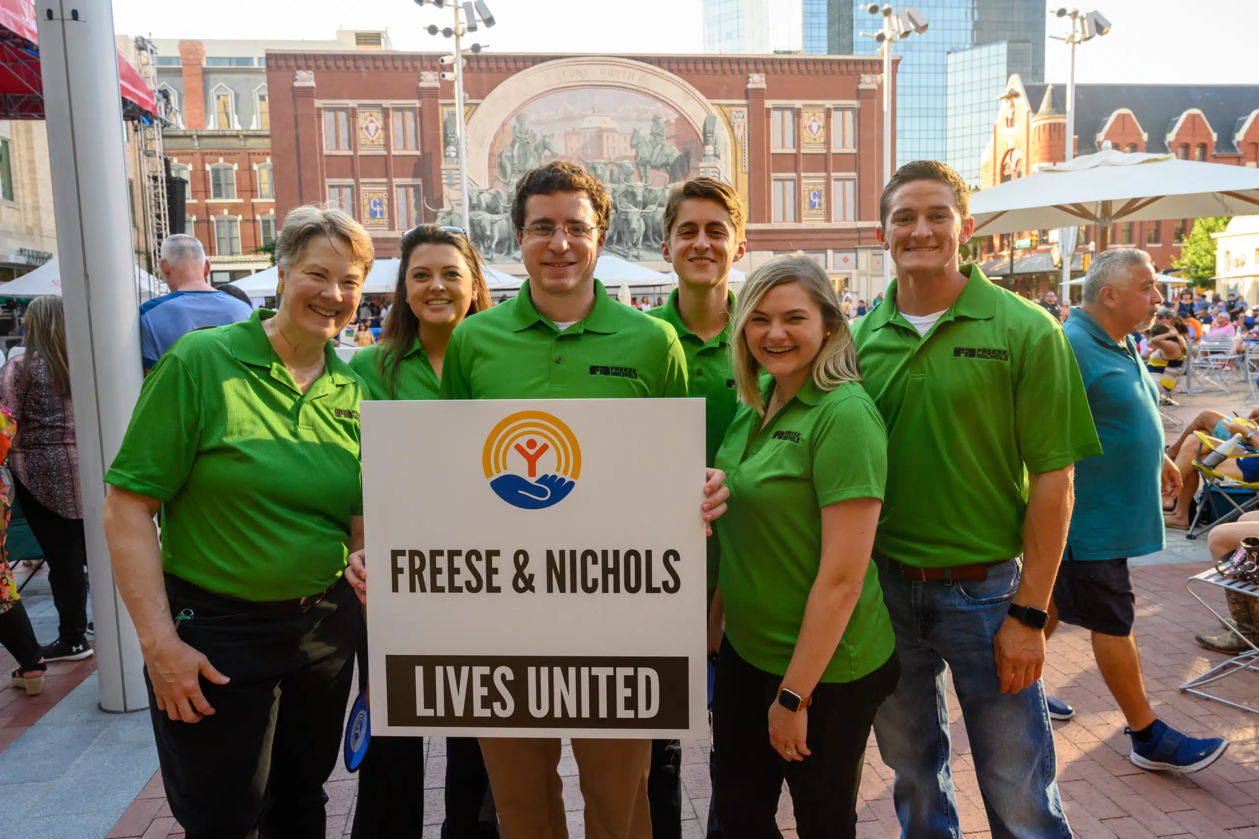 Six employees gathered around a United Way sign in Sundance Square of Fort Worth